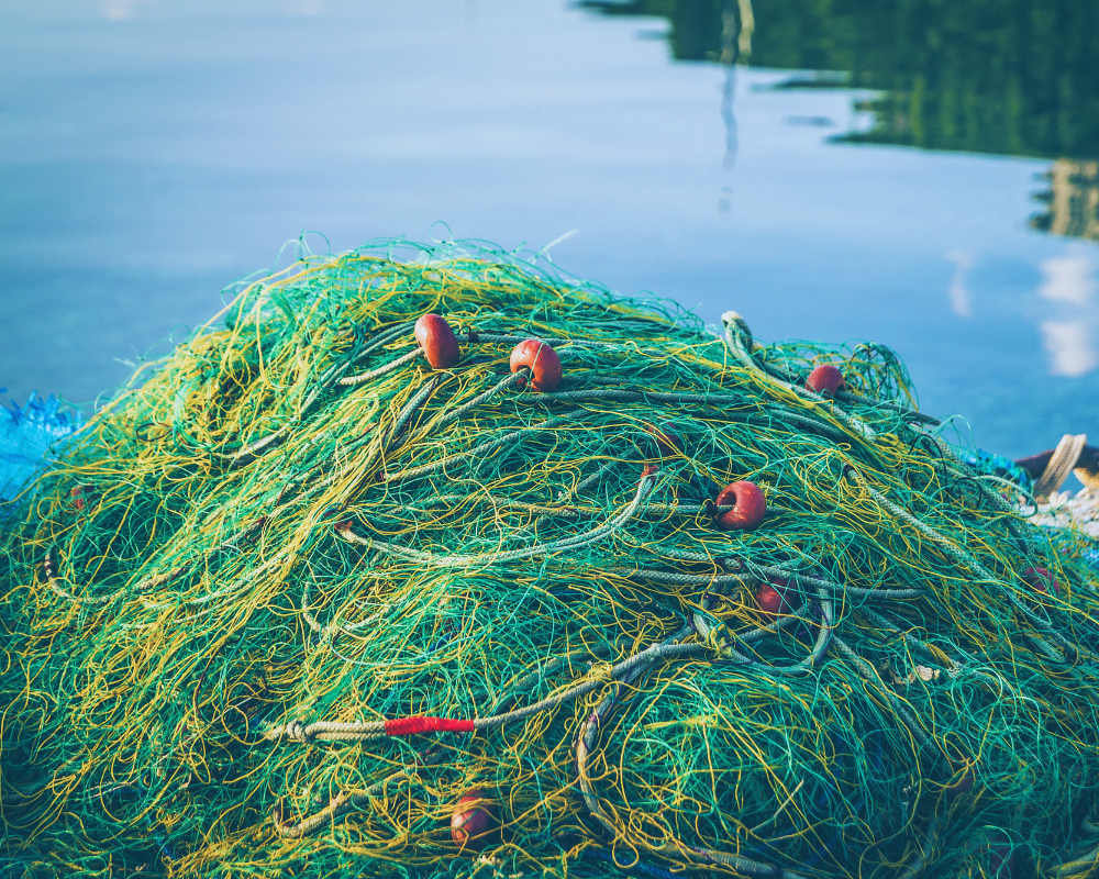 A pile of fishing nets next to a body of water